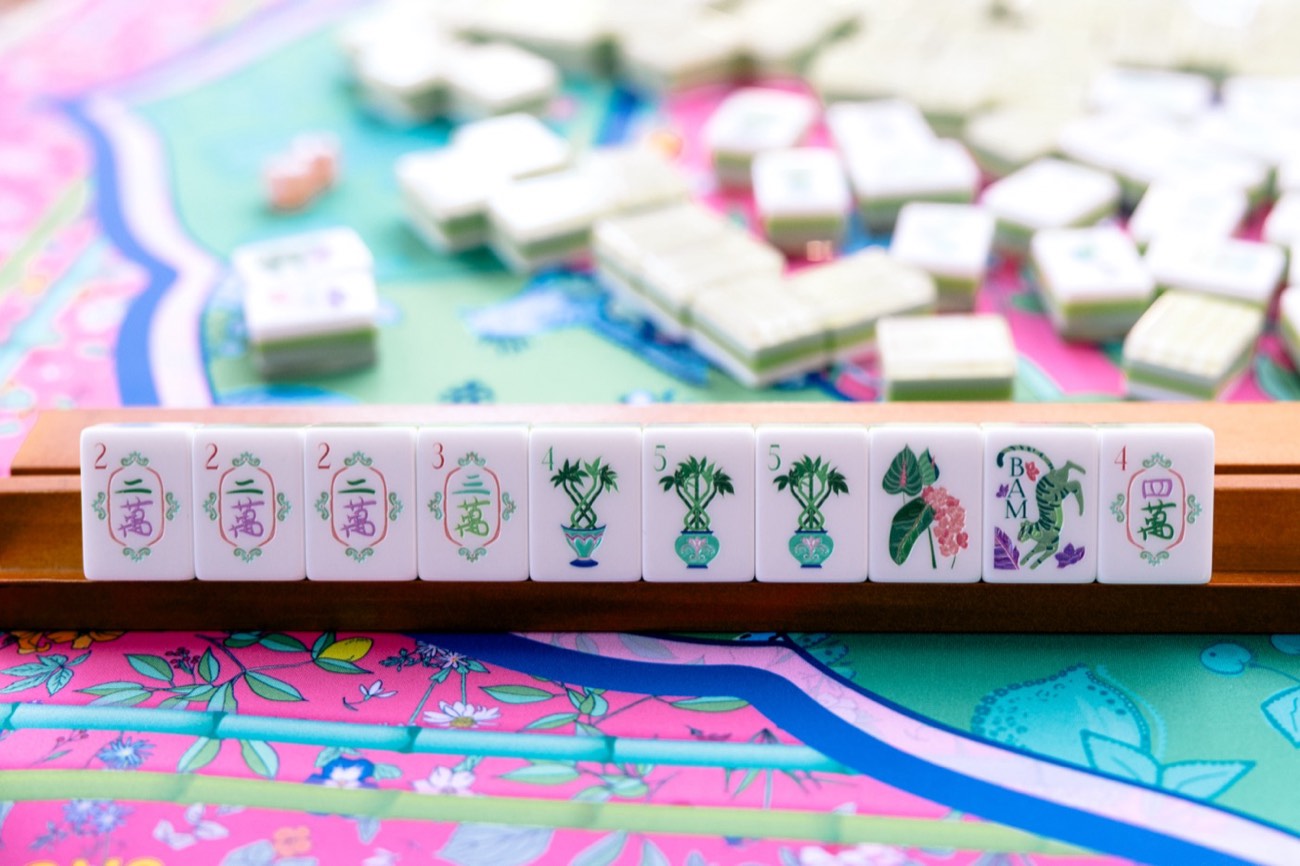 A rack of hand-painted Mahjong tiles on a floral table mat